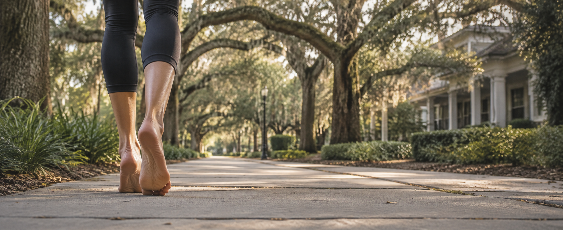 Bare feet walking along a sunlit tree-lined street